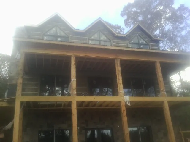 Dormers and porch framing on a large log home under construction — Roof Coating work by our crew in Riverdale