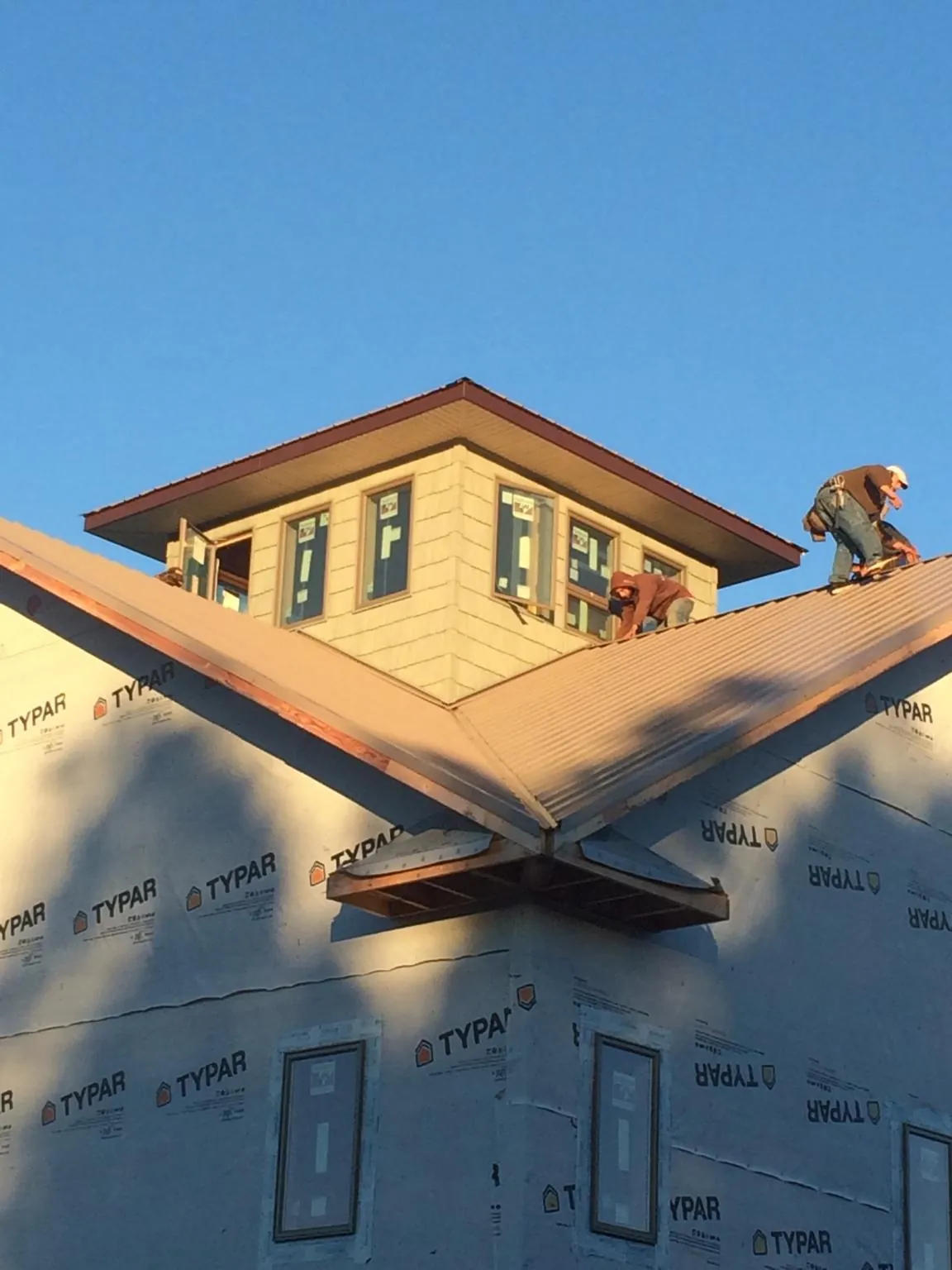 Roofers working around a rooftop cupola on a new metal roof at sunset — Roof Waterproofing in Riverdale by Roofing Brothers